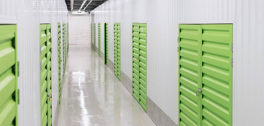 Lagerlokale i Stockholm med lysegrønne opbevaringsdøre organiseret i en ren, godt oplyst korridor, der fremhæver sikkerhedsfunktioner og moderne faciliteter, ideelt for midlertidig opbevaring af ejendele.